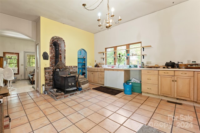 interior space featuring tile patterned flooring, a wood stove, a chandelier, and visible vents