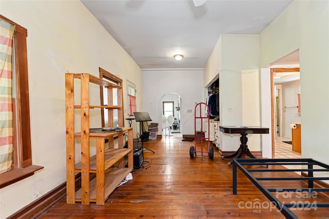 interior space with wood-type flooring, arched walkways, and baseboards