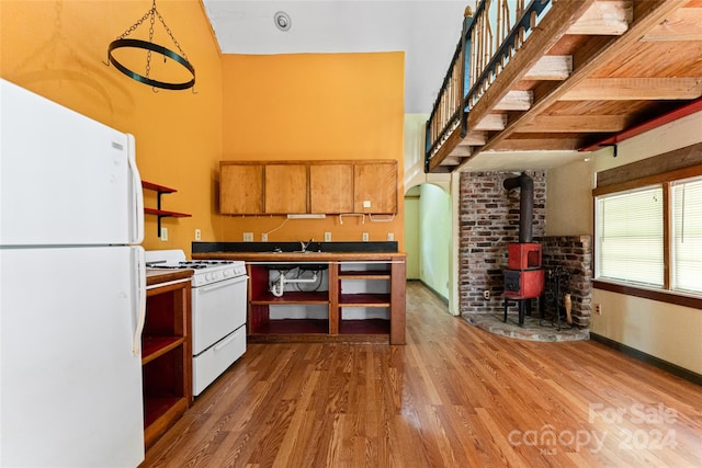 kitchen with open shelves, a wood stove, white appliances, and wood finished floors