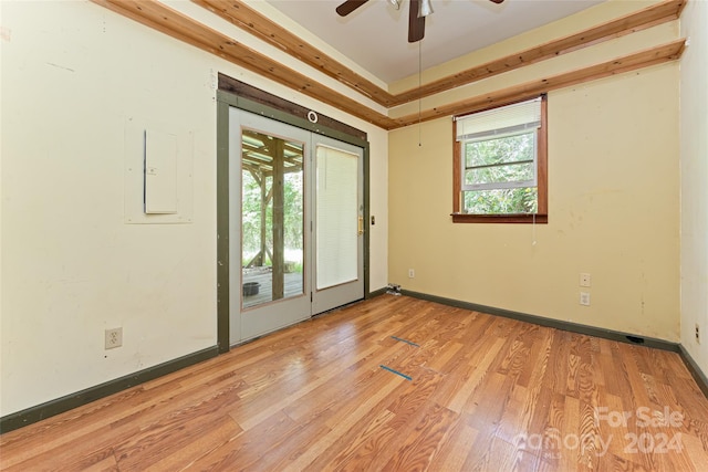 unfurnished room with baseboards, ceiling fan, a tray ceiling, and light wood finished floors