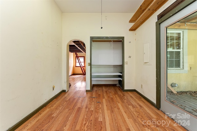 unfurnished bedroom featuring light wood-style floors, arched walkways, and baseboards