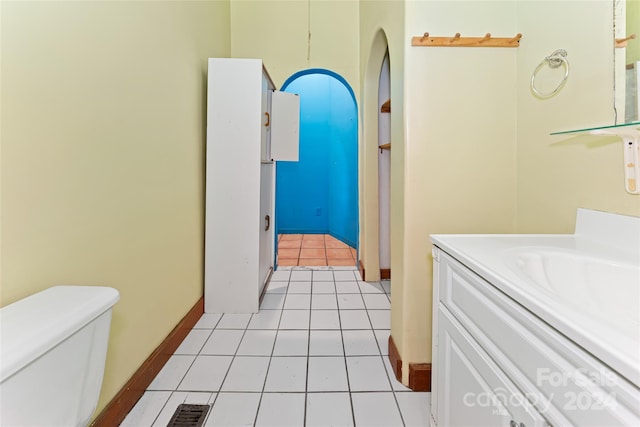 half bath featuring vanity, toilet, tile patterned floors, baseboards, and visible vents