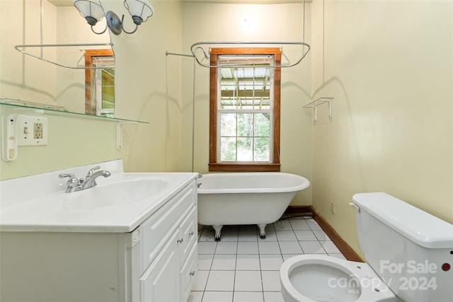bathroom with a freestanding bath, tile patterned flooring, vanity, toilet, and baseboards