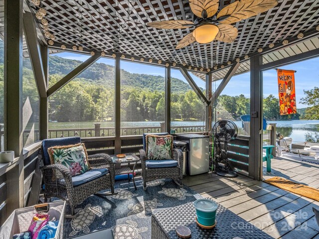 sunroom / solarium with a wealth of natural light, a water and mountain view, and ceiling fan