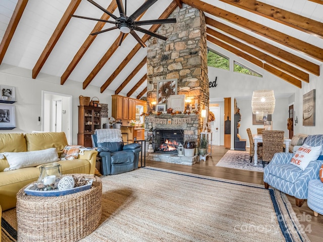 living room featuring hardwood / wood-style flooring, beamed ceiling, ceiling fan, a stone fireplace, and high vaulted ceiling