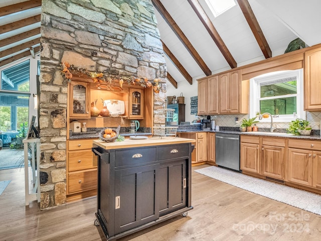 kitchen featuring a wealth of natural light, stainless steel dishwasher, light hardwood / wood-style flooring, and a skylight