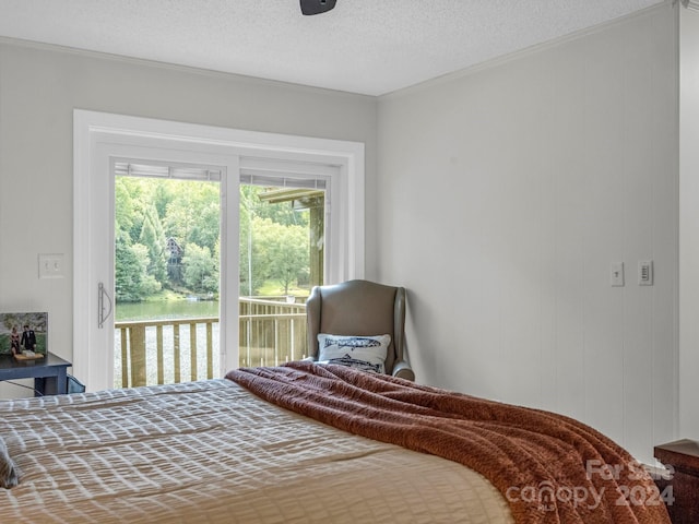 bedroom with a water view, a textured ceiling, access to outside, and ornamental molding