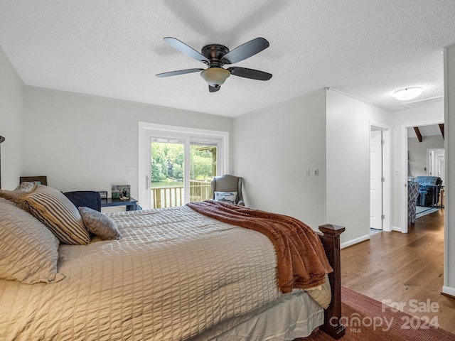 bedroom with a textured ceiling, ceiling fan, and hardwood / wood-style floors