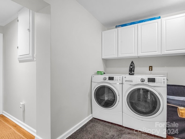 laundry room featuring washer and clothes dryer, hardwood / wood-style flooring, and cabinets