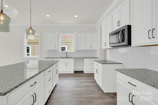 kitchen featuring ornamental molding, decorative light fixtures, stone counters, dark hardwood / wood-style floors, and tasteful backsplash