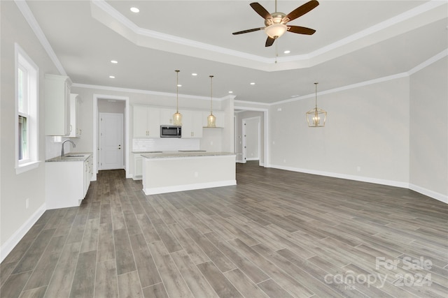 unfurnished living room with crown molding, a tray ceiling, and light hardwood / wood-style floors