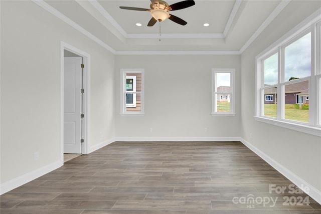 unfurnished room featuring ceiling fan, ornamental molding, a tray ceiling, and wood-type flooring