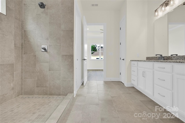 bathroom with tiled shower, tile patterned flooring, and vanity