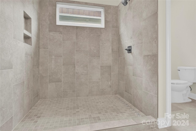 bathroom featuring tile patterned floors, tiled shower, and toilet