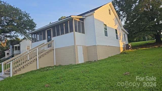 view of property exterior with a garage, a sunroom, stairs, and a yard