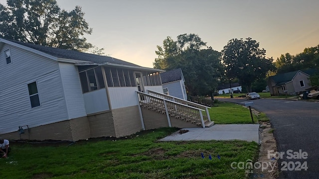 view of side of property featuring stairs, a lawn, and a sunroom