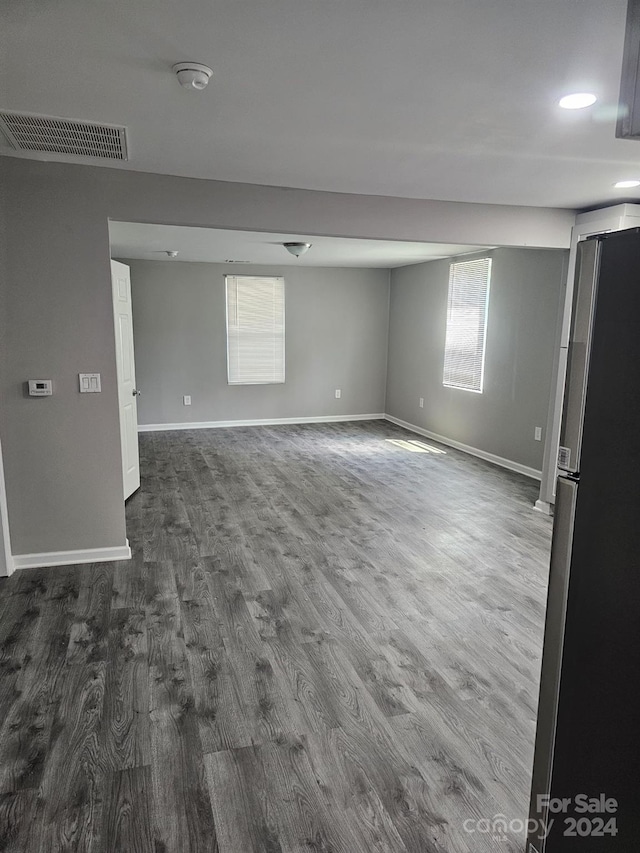 empty room featuring dark wood-type flooring, visible vents, and baseboards