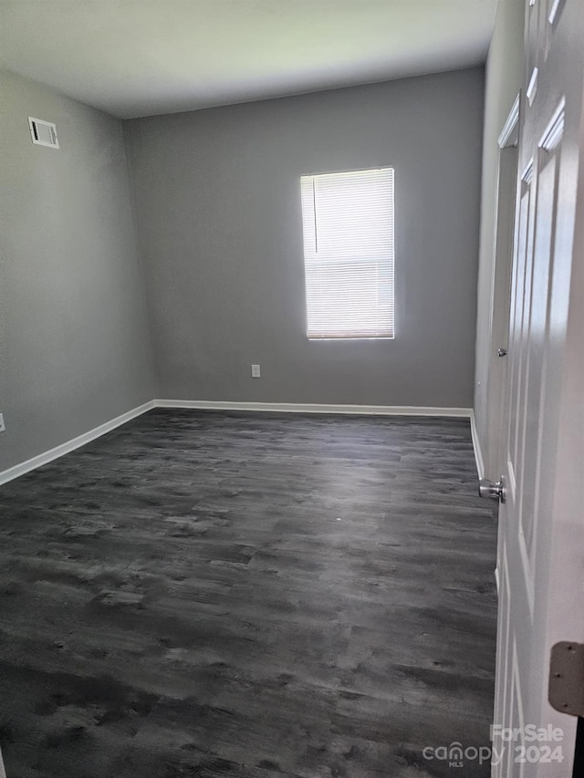 interior space featuring dark wood-style flooring, visible vents, and baseboards