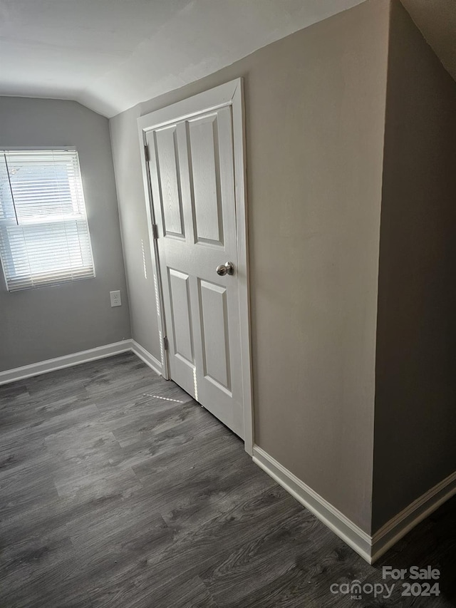 interior space featuring lofted ceiling, dark wood-style flooring, and baseboards