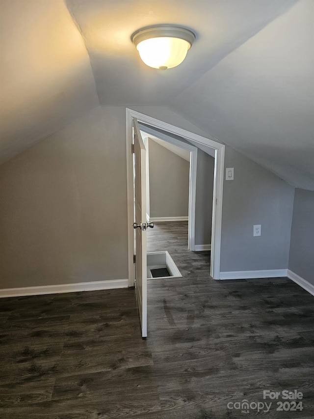 additional living space with lofted ceiling, baseboards, and dark wood finished floors