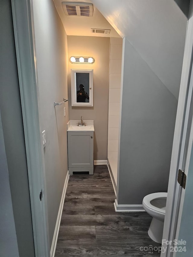 bathroom with toilet, visible vents, wood finished floors, and vanity