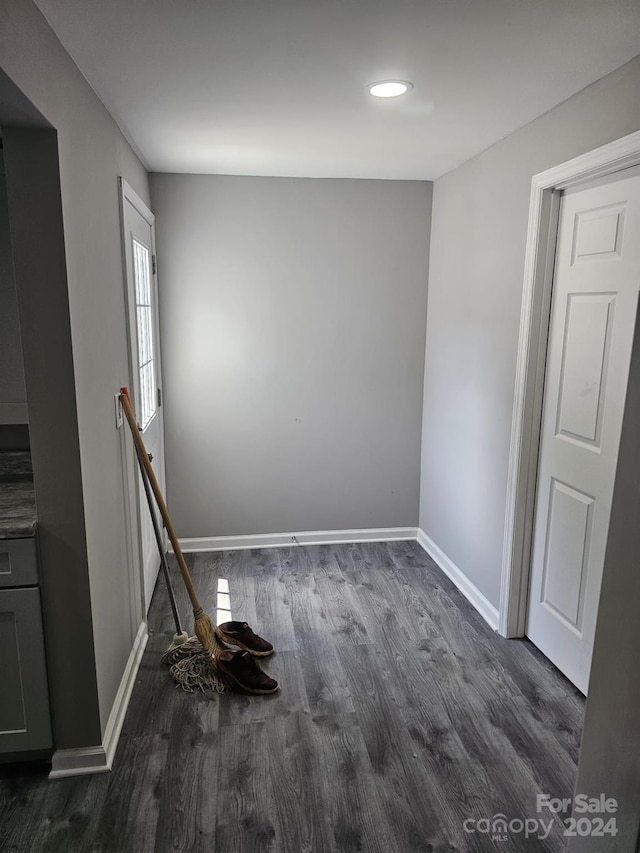 spare room featuring baseboards and dark wood-type flooring