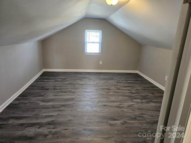 bonus room featuring dark wood-style floors, vaulted ceiling, and baseboards