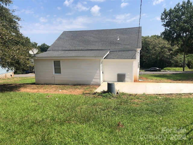 back of house with a shingled roof and a lawn