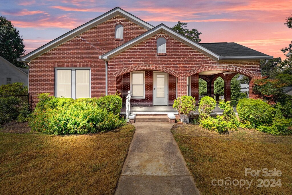view of front of house featuring brick siding, a porch, and a front lawn