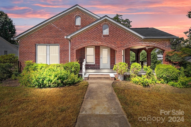 view of front of house featuring brick siding, a porch, and a front lawn