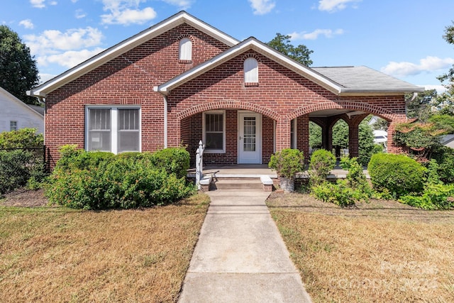 view of front of house featuring brick siding, a porch, and a front lawn