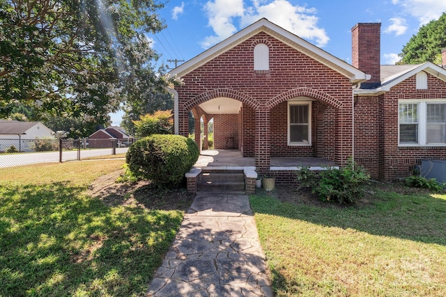 view of front of property with a front lawn, fence, brick siding, and a chimney