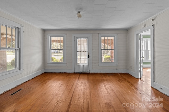 doorway with light hardwood / wood-style floors, a healthy amount of sunlight, and crown molding