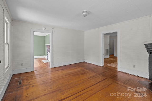 empty room featuring hardwood / wood-style floors, plenty of natural light, and ornamental molding