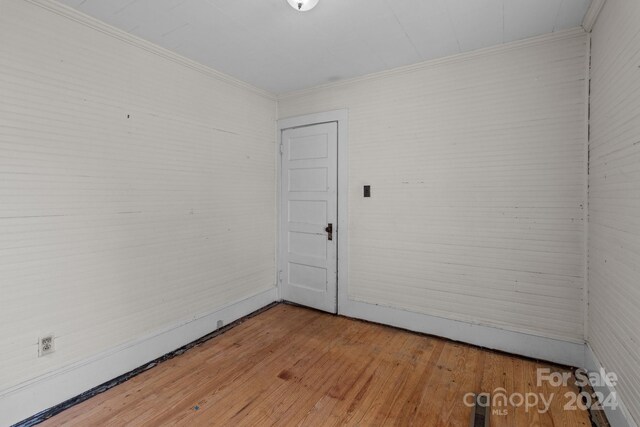 empty room featuring crown molding and wood-type flooring