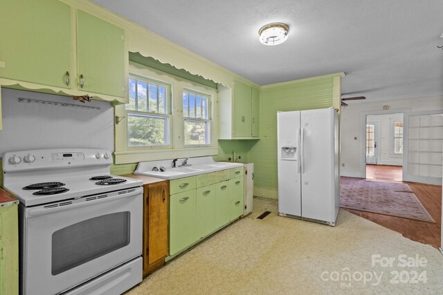 kitchen with light wood-type flooring, sink, white appliances, and green cabinetry