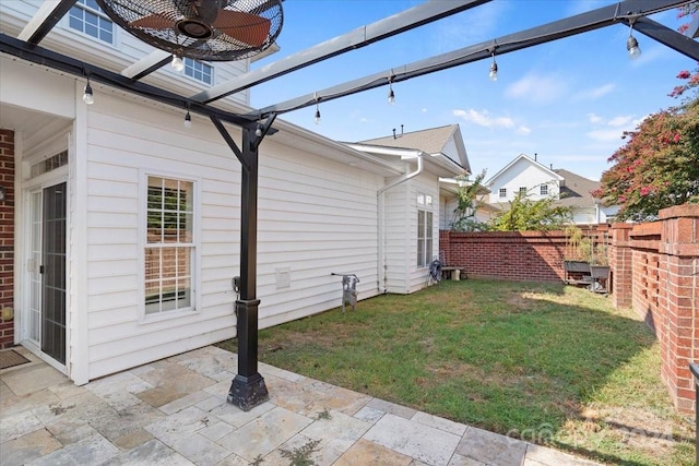 view of side of property featuring ceiling fan, a lawn, and a patio