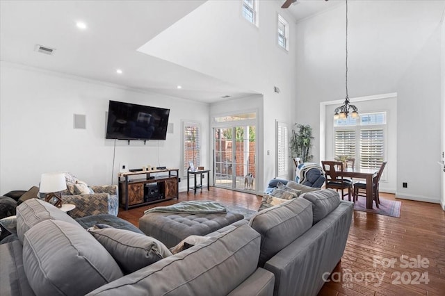 living room featuring ceiling fan with notable chandelier, a towering ceiling, and dark hardwood / wood-style floors