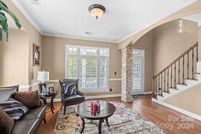 living room with crown molding, wood-type flooring, and ornate columns