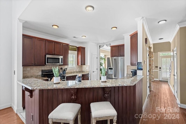 kitchen with light wood-type flooring, appliances with stainless steel finishes, decorative backsplash, and a healthy amount of sunlight