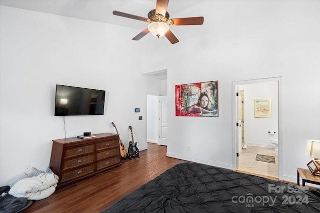 tiled bedroom with connected bathroom, a towering ceiling, and ceiling fan