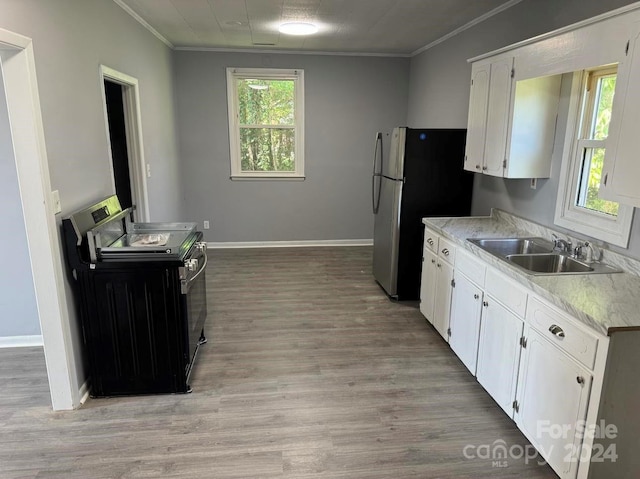 kitchen with crown molding, electric stove, freestanding refrigerator, and white cabinetry