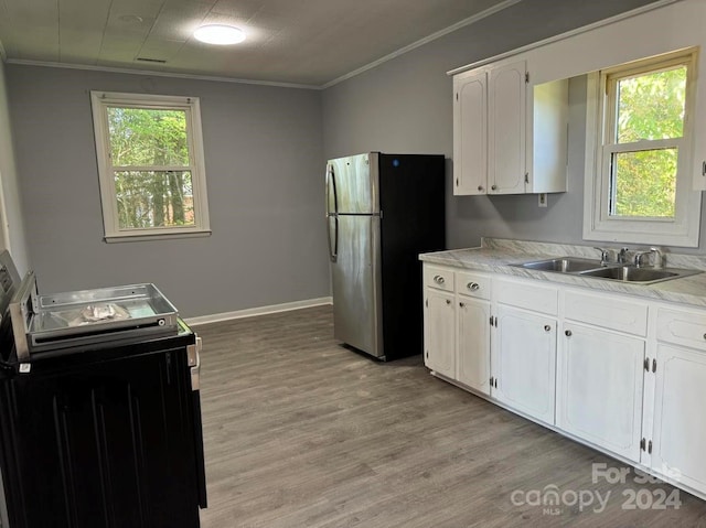 kitchen with ornamental molding, white cabinets, a sink, and freestanding refrigerator