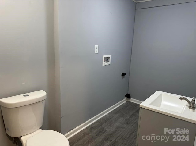 bathroom with toilet, vanity, baseboards, and wood finished floors