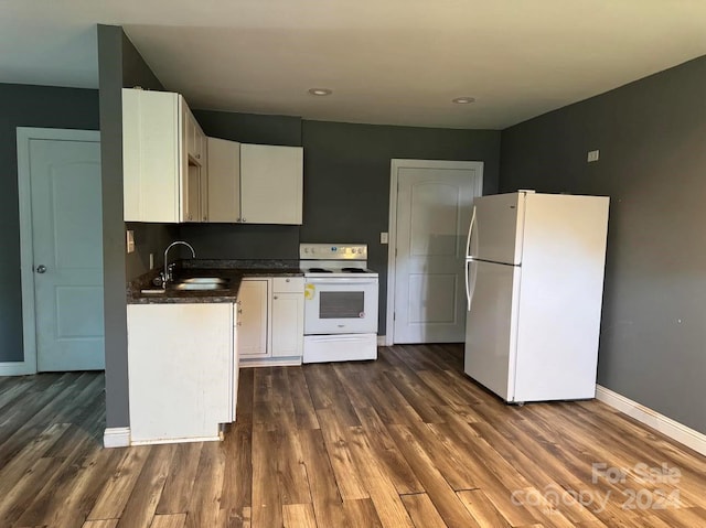 kitchen featuring dark countertops, white appliances, white cabinetry, and a sink