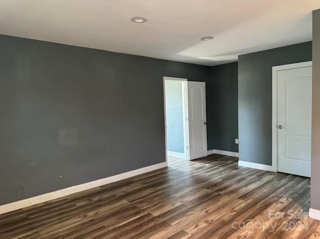 unfurnished bedroom with baseboards and dark wood-type flooring