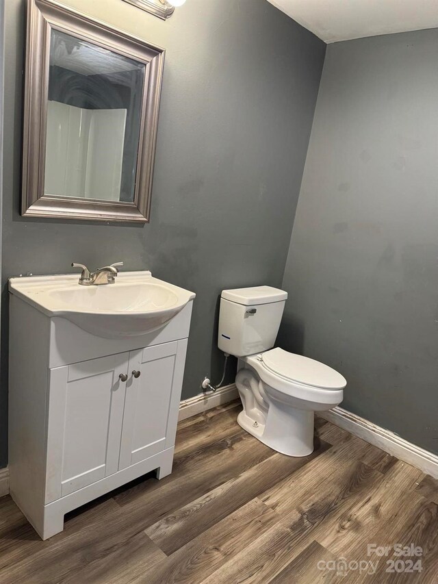 bathroom with baseboards, vanity, toilet, and wood finished floors