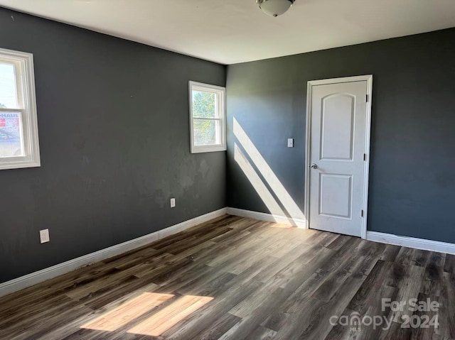 spare room with dark wood-type flooring and baseboards