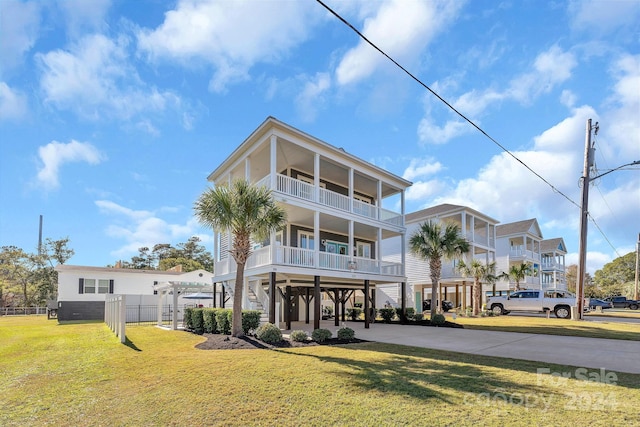 coastal inspired home with a carport, a balcony, and a front lawn