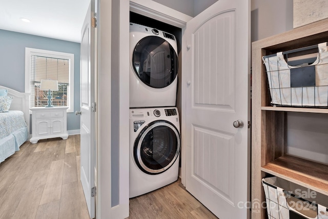 laundry area featuring stacked washing maching and dryer and light wood-type flooring